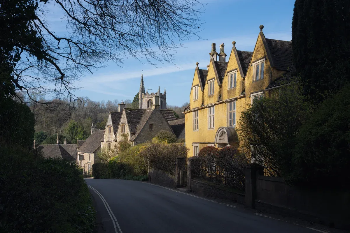 Honey-coloured houses and church at Castle Combe village on a small group Cotswolds day trip from London